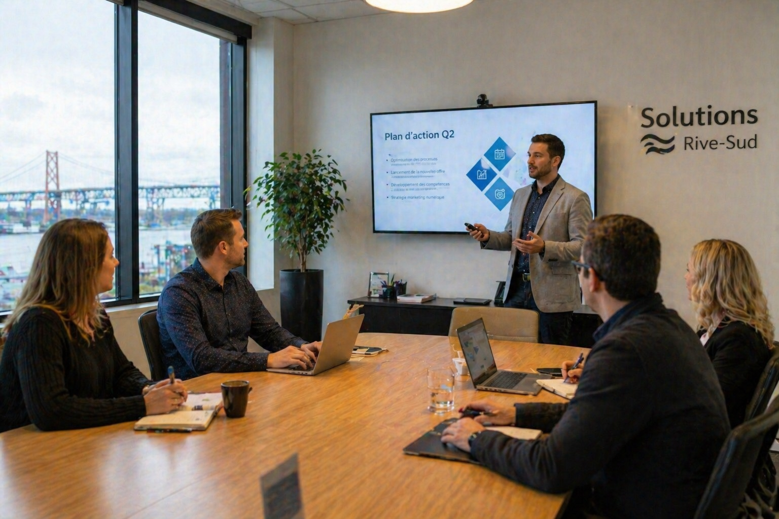 Equipe de PME Solutions Rive-Sud a Levis en reunion de planification strategique Q2 - presentation plan d action avec objectifs d optimisation des processus, lancement nouvelle offre et strategie marketing numerique - vue sur le fleuve Saint-Laurent et le pont de Quebec en arriere-plan